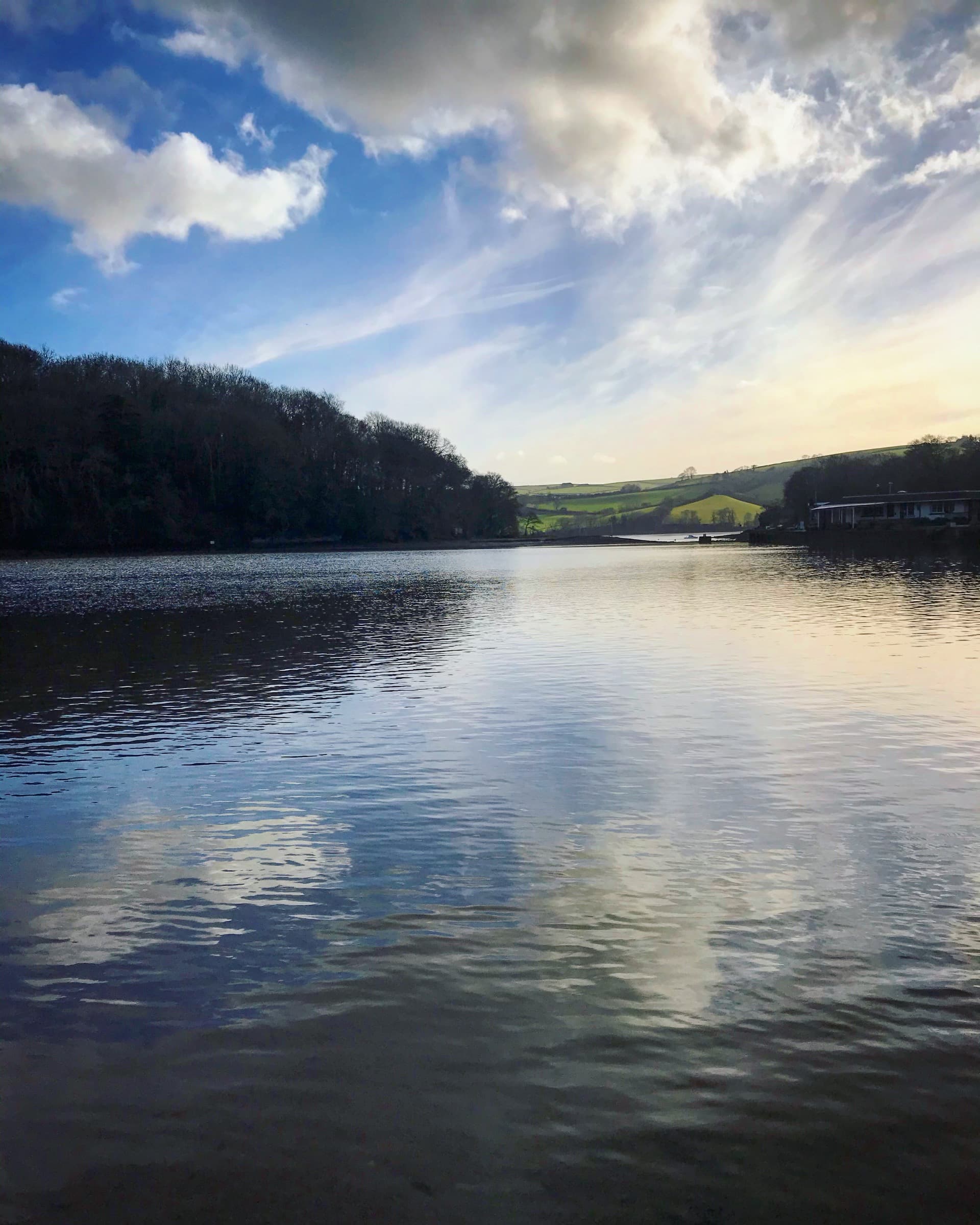The River Dart at dusk, with wooded banks and fields beyond