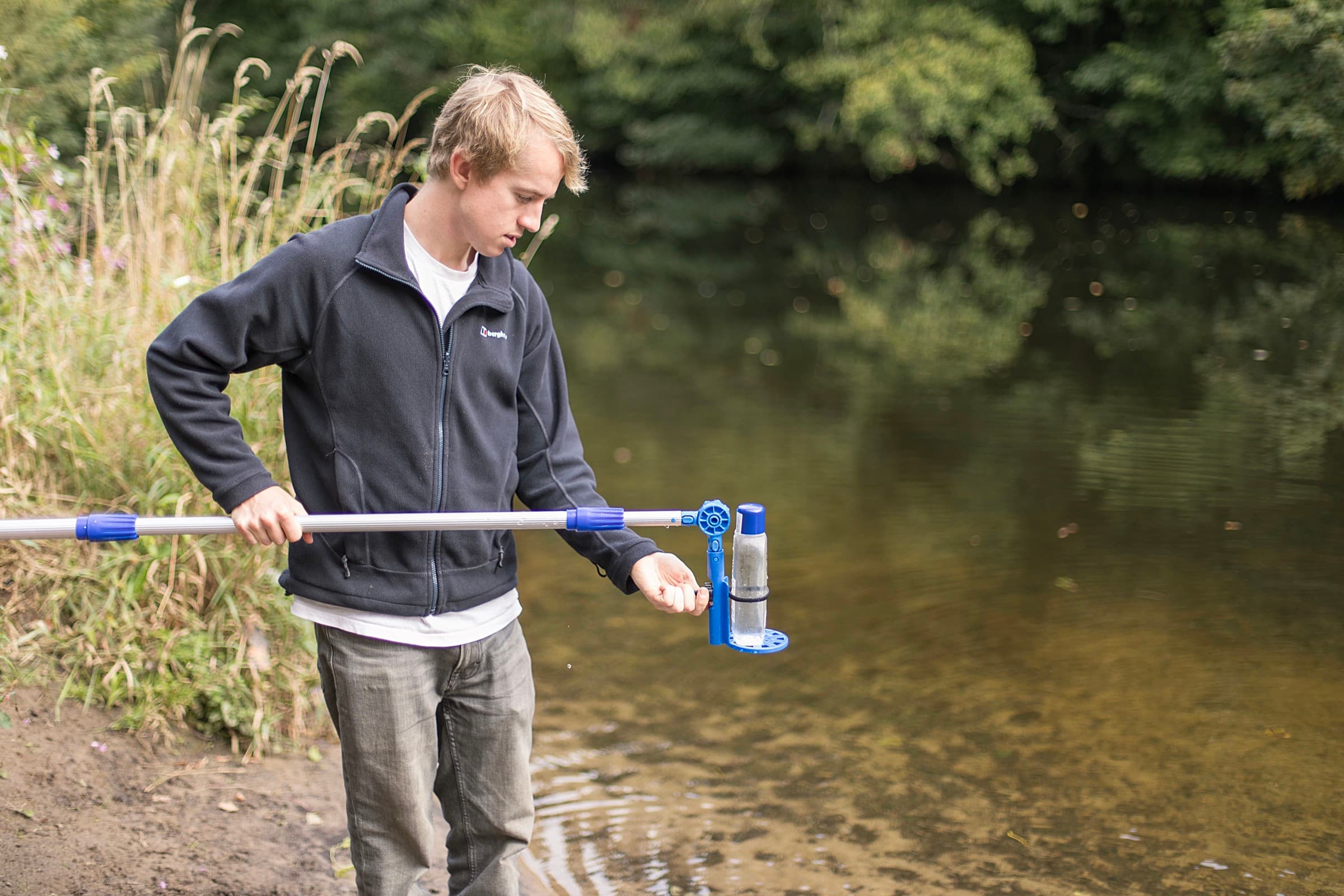 A volunteer taking a water sample with a sampling pole